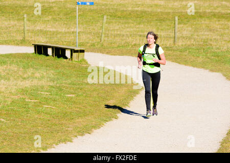 Kaseberga, Sweden - April 1, 2016: Female jogger running at gravel path surrounded by grass. Real people in everyday life in pub Stock Photo