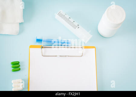Medical conceptual picture with pills, injection, gauze, bottle, empty clipboard sheet. Stock Photo