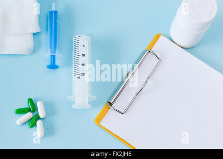 Medical conceptual picture with pills, injection, gauze, bottle, empty clipboard sheet. Stock Photo