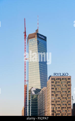 Modern office block in Warsaw under construction with a crane and climbing workers. A skyscraper in postmodernist style Stock Photo