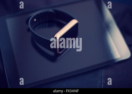 Smart wrist watch laying on a talbet pc. This gadgets will let you always stay connected to the social media and internet technologies. Work and have fun from anywhere you want. Blue hipster toning Stock Photo