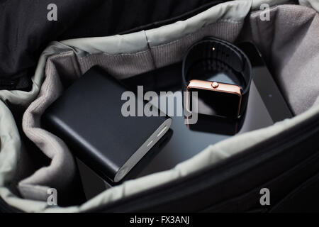 Portable clever technology of today. Smart wrist watch, tablet pc and powerbank charger in a travel bag. All you need to always stay connected to the internet and social media networks. Stock Photo