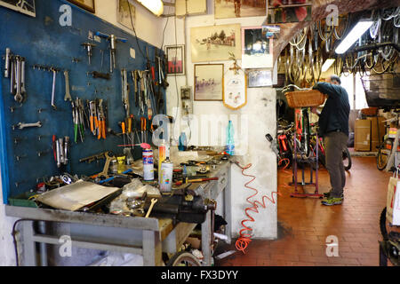 Interior of the cycle workshop of Poli in Lucca, Tuscany. Italy. Showing work bench and tools, mechanic and various memorabilia Stock Photo