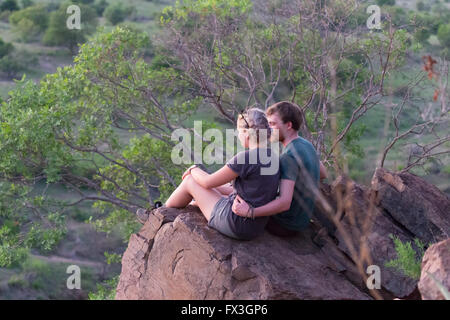 A young could sit on a rock overlooking a sunset in Kruger National Park Stock Photo
