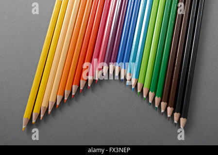 Colored Pencils arranged into a V pattern, set against a gray background. Stock Photo