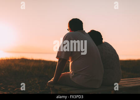 Side view a married couple a silhouette sitting on a bench. Stock Photo