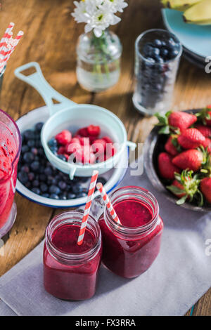 Two jars with berry smoothie, fresh fruits in background. Clean eating and dieting concept Stock Photo