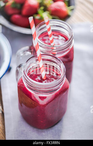 Dieting and well being concept, berry smoothie in jar, view from above on wooden table in sunny kitchen Stock Photo