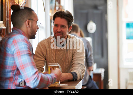 Two Male Friends Enjoying Drink In Bar Stock Photo