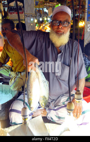 (160411) -- DHAKA, April 11, 2016 (Xinhua) -- A fish trader shows hilsha fish to customers at a fish market ahead of the upcoming Bengali New Year in Dhaka, Bangladesh, April 11, 2016. Bangladeshi people will celebrate Bengali New Year on April 14 this year. (Xinhua/Shariful Islam) Stock Photo