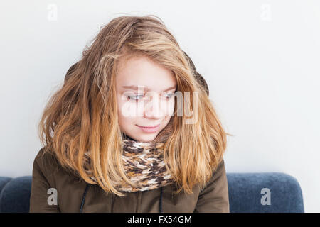 Close up portrait of beautiful blond Caucasian teenage girl in warm scarf over white wall background Stock Photo