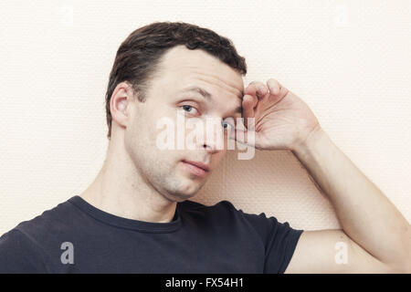 Young thinking Caucasian man, portrait over gray wall background Stock Photo