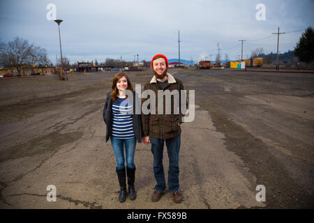 Modern, trendy, hipster couple in an abandoned train yard at dusk in this fashion style portrait. Stock Photo