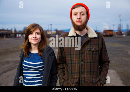 Modern, trendy, hipster couple in an abandoned train yard at dusk in this fashion style portrait. Stock Photo