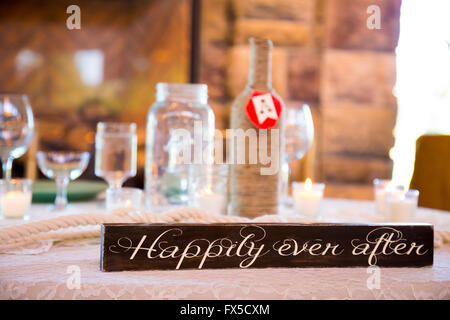 Wedding decor sign that says happily ever after with reception details blurred out of focus in the background. Stock Photo