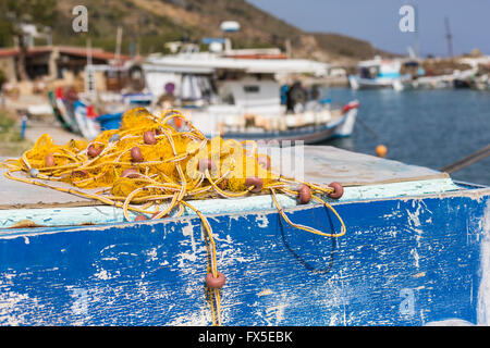 Fishing nets and Greek fishing boats mooring in port in sunrise light, Crete island, Greece Stock Photo