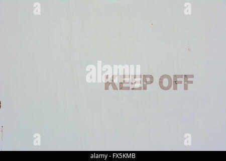 Keep Off hand painted sign against a plain white metal background Stock Photo