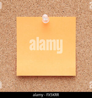 Closeup of a orange note paper on a corkboard Stock Photo