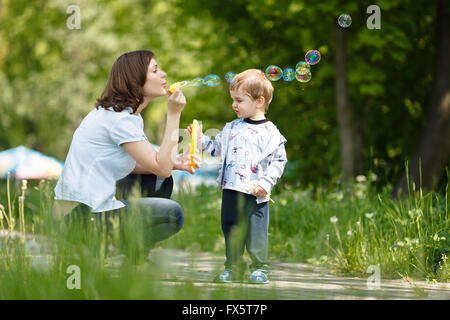 Mother with her son blowing bubbles at summer day