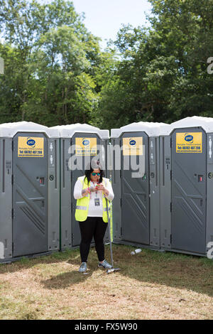 Womad festival, wiltshire and a  Toilet attendent looking at her mobiel phone. Stock Photo