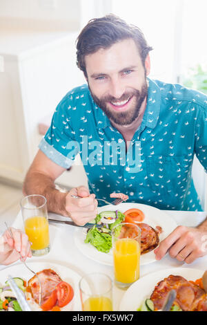 Young man sitting at dining table smiling Stock Photo