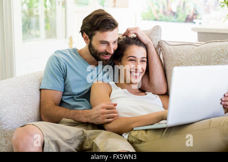 Couple sitting on sofa and using laptop Stock Photo