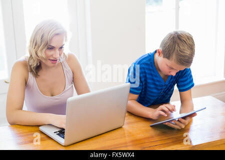 Happy mother and son using laptop and digital tablet Stock Photo