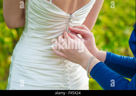 Bridesmaid is helping the bride to dress in weddihg day Stock Photo