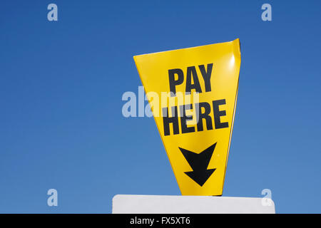 Yellow Pay Here sign against a blue sky