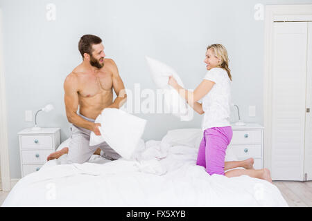 Couple having a pillow fight in bed Stock Photo