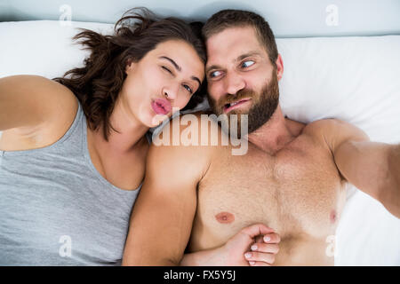 Couple making funny faces on bed Stock Photo
