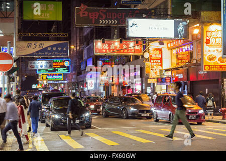 People and cars at a street in Kowloon, Hong Kong, China, at night. Stock Photo