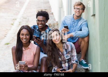 Friends sitting together using mobile phone Stock Photo