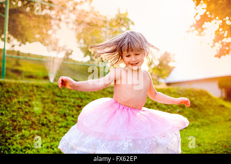 Girl in princess skirt spinning in sunny summer garden Stock Photo