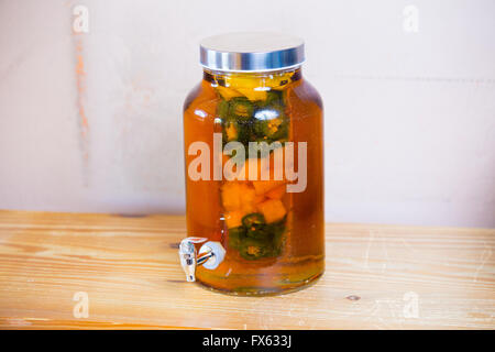 Tequila infused with jalapeno peppers in a tea jar at a restaurant bar. Stock Photo