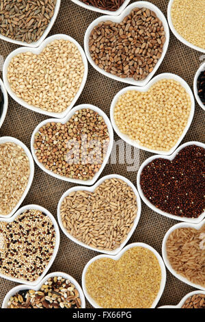 Grain and cereal food selection in heart shaped porcelain bowls over hessian background. Stock Photo