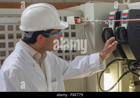 Hispanic technician checking machinery in factory Stock Photo