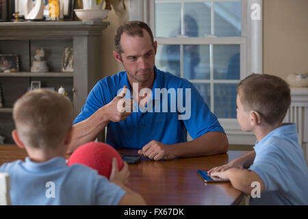 Caucasian father and sons signing at dinner table Stock Photo