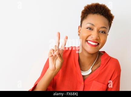 Mixed race woman making peace sign Stock Photo