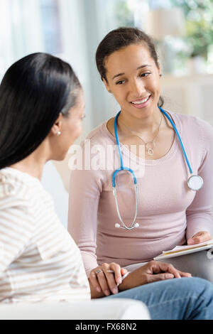 Doctor comforting patient in living room Stock Photo