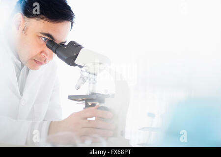 Mixed race scientist using microscope Stock Photo