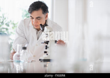 Mixed race scientist using microscope in laboratory Stock Photo
