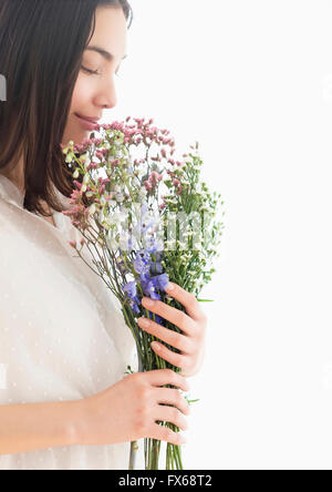 Hispanic woman smelling bouquet of flowers Stock Photo