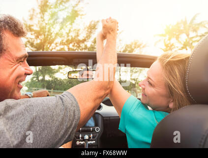 Caucasian couple holding hands in convertible Stock Photo