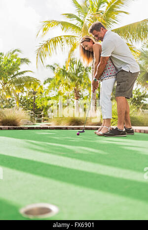 Caucasian couple playing miniature golf Stock Photo