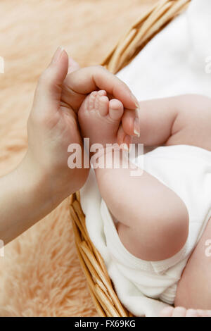 Mother holds little foot of her newborn baby Stock Photo