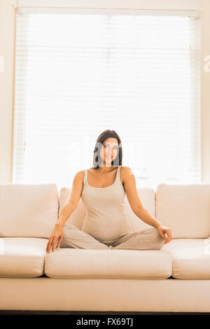 Pregnant Caucasian woman sitting on sofa Stock Photo