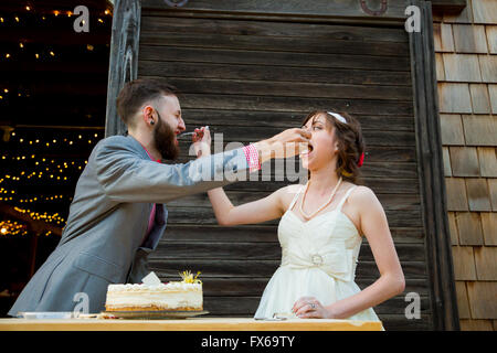 Bride and groom cut the cake and feed each other on their wedding day at the reception. Stock Photo