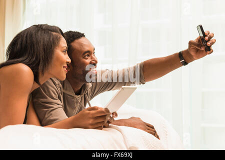 Couple taking selfie on bed Stock Photo