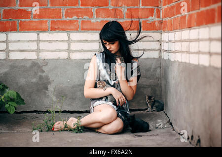 Caucasian woman sitting on sidewalk with cats Stock Photo